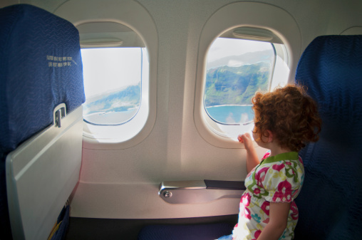 Little girl looking out an airplane window.